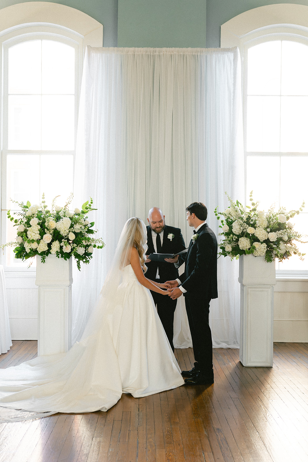 A bride and groom stand with an officiant during their wedding ceremony at Stanly Hall Ballroom