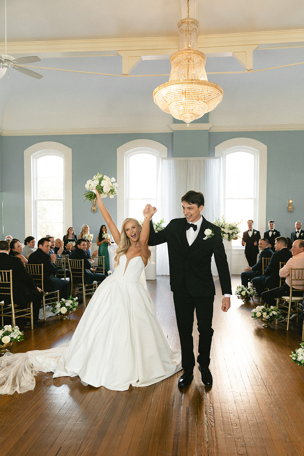 A bride and groom stand with an officiant during their wedding ceremony at Stanly Hall Ballroom