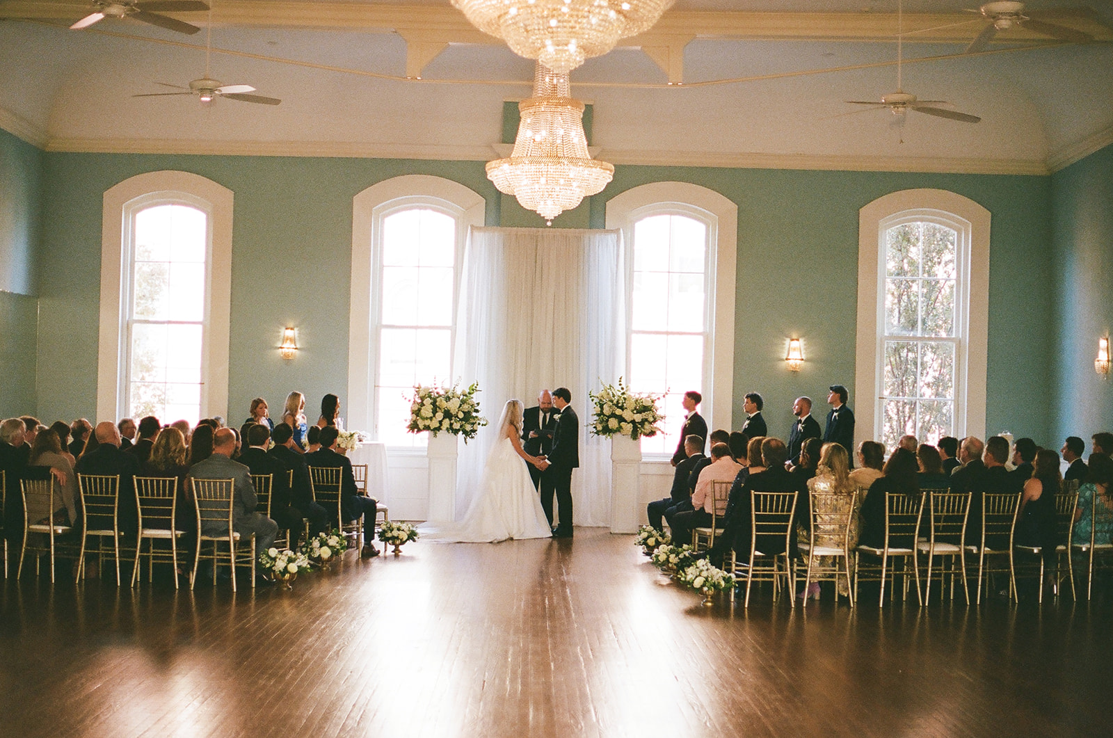 A bride and groom stand with an officiant during their wedding ceremony at Stanly Hall Ballroom