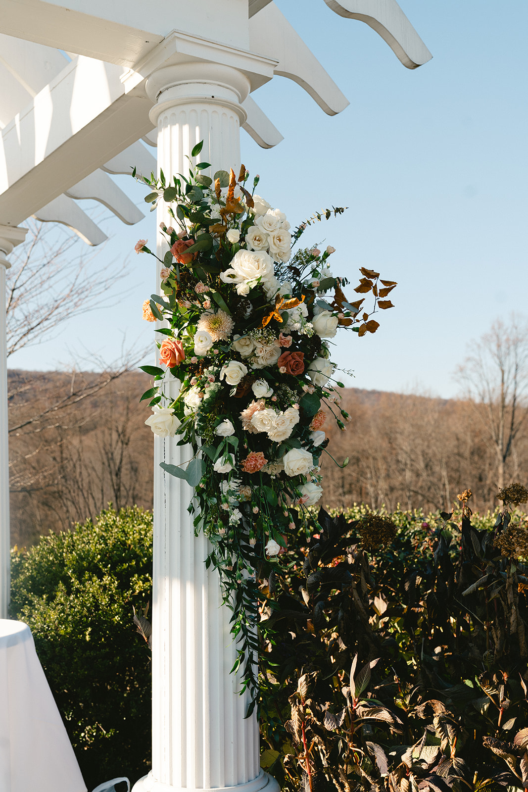 A group of people in formal black attire stand on grass outside a building, gathered closely together while taking a selfie.