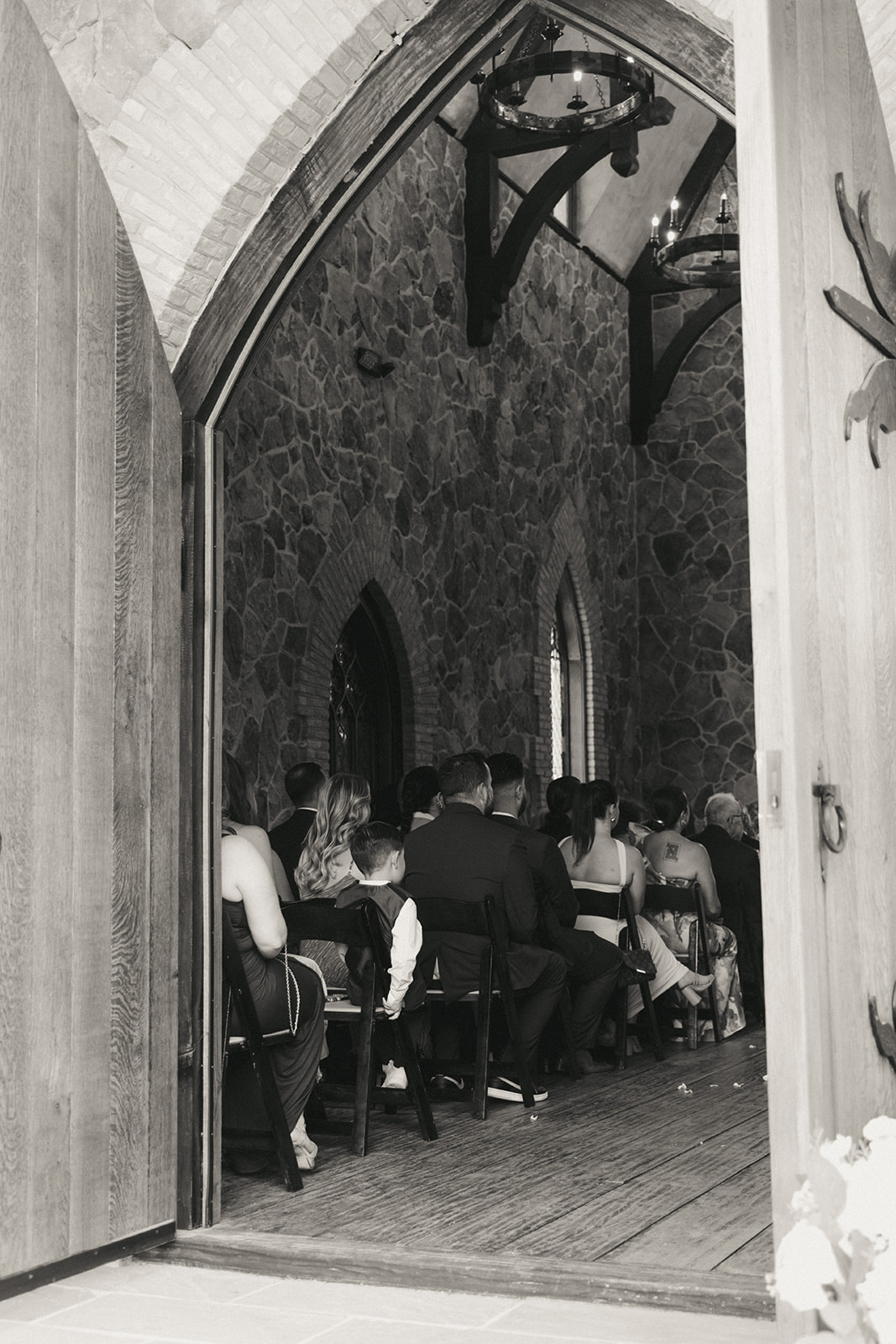 A bride and groom stand at the altar with an officiant in a stone chapel, surrounded by seated guests at the little chapel at haven ridge a wedding venue in North Carolina 