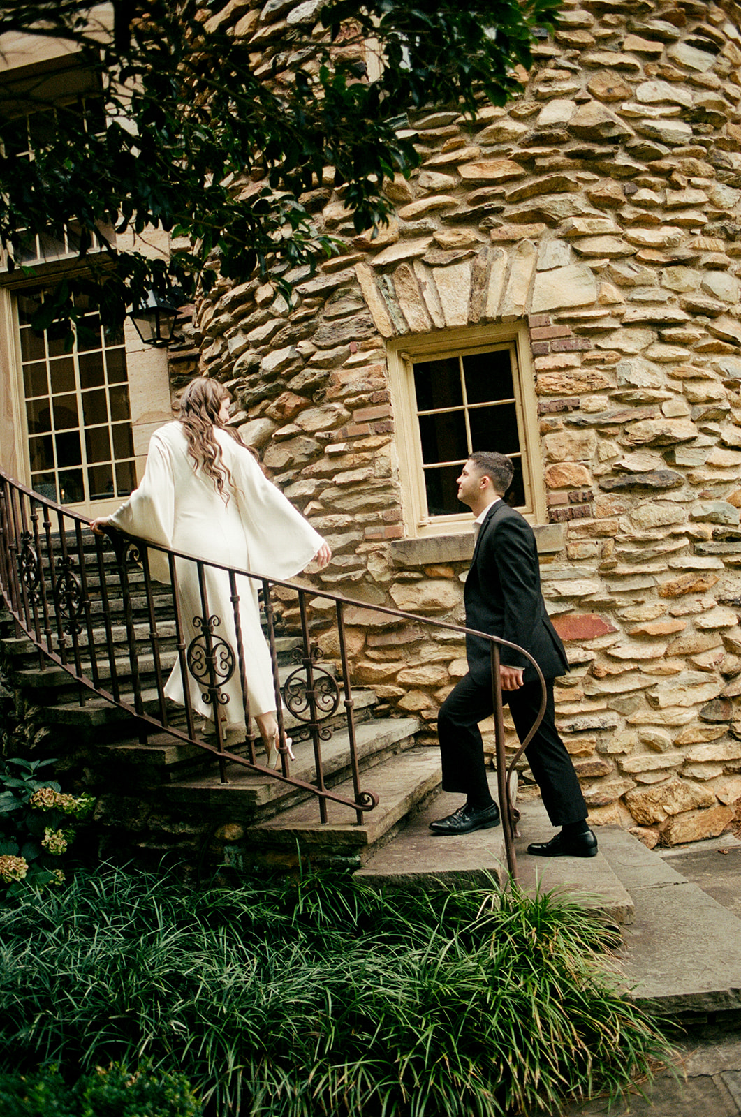 A person in a suit and a person in a white dress while standing in a garden with blooming white flowers at Graylyn Estate a wedding venue in North Carolina