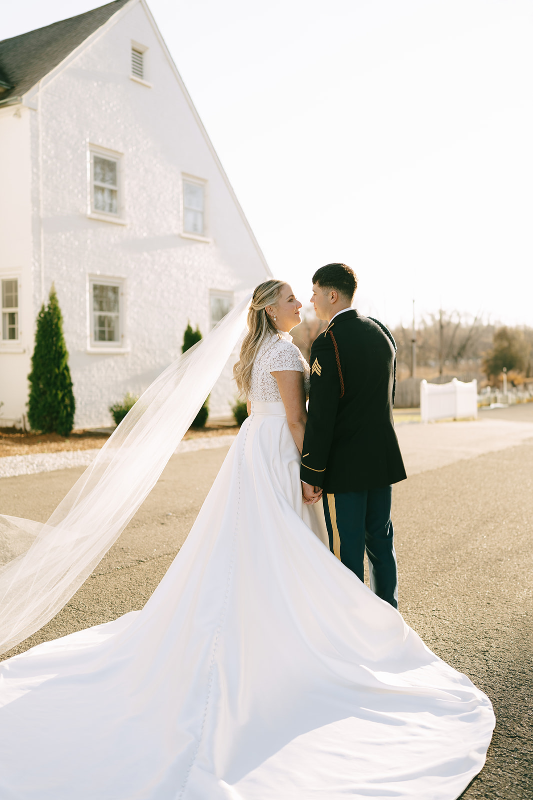 A bride and groom in wedding attire share a kiss outdoors on a sunny day at The Vintage Oak Estate a wedding venue in North Carolina 